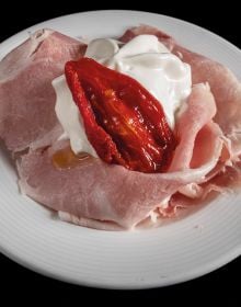 Book cover of Sabatino Sorrentino's La Merenda Italiana: con i migliori salumi d'Italia, with a pastry parcel topped with prosciutto and cheese. Published by Manfredi Edizioni.