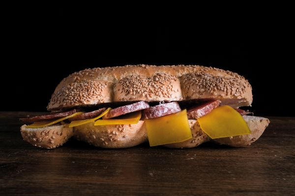 Book cover of Sabatino Sorrentino's La Merenda Italiana: con i migliori salumi d'Italia, with a pastry parcel topped with prosciutto and cheese. Published by Manfredi Edizioni.