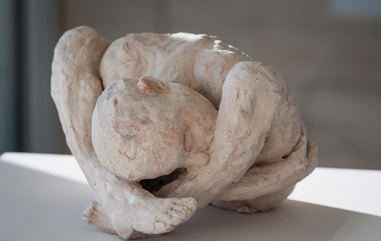 Life sized clay sculpture of girl sitting on bed, Breath in pale grey font above