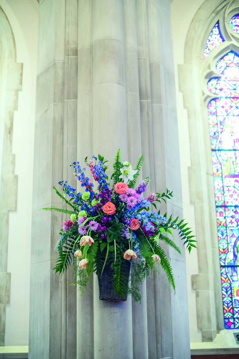 Book cover of Laura Larocci's Faith Flowers, Celebrate With a Glorious Array of Flowers with a church pew decorated with pink roses, white lilies and green fern fronds. Published by Stichting.