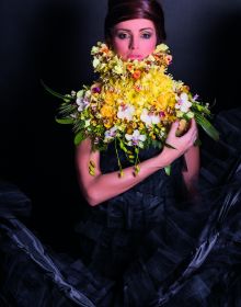 White book cover of International Floral Art 2018/2019, with a model wearing white face paint, and a head-dress of white flowers cascading down. Published by Stichting.