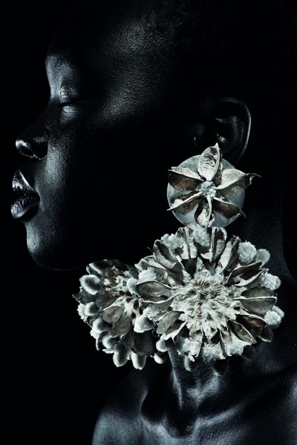 White book cover of International Floral Art 2018/2019, with a model wearing white face paint, and a head-dress of white flowers cascading down. Published by Stichting.