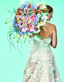 Book cover of The World of Colour According to Per Benjamin, with a model wearing a ring of pink and yellow lilies around neck, with long thin feathers spraying out. Published by Stichting.