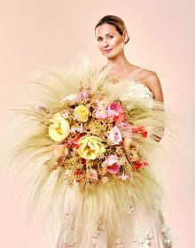 Book cover of The World of Colour According to Per Benjamin, with a model wearing a ring of pink and yellow lilies around neck, with long thin feathers spraying out. Published by Stichting.