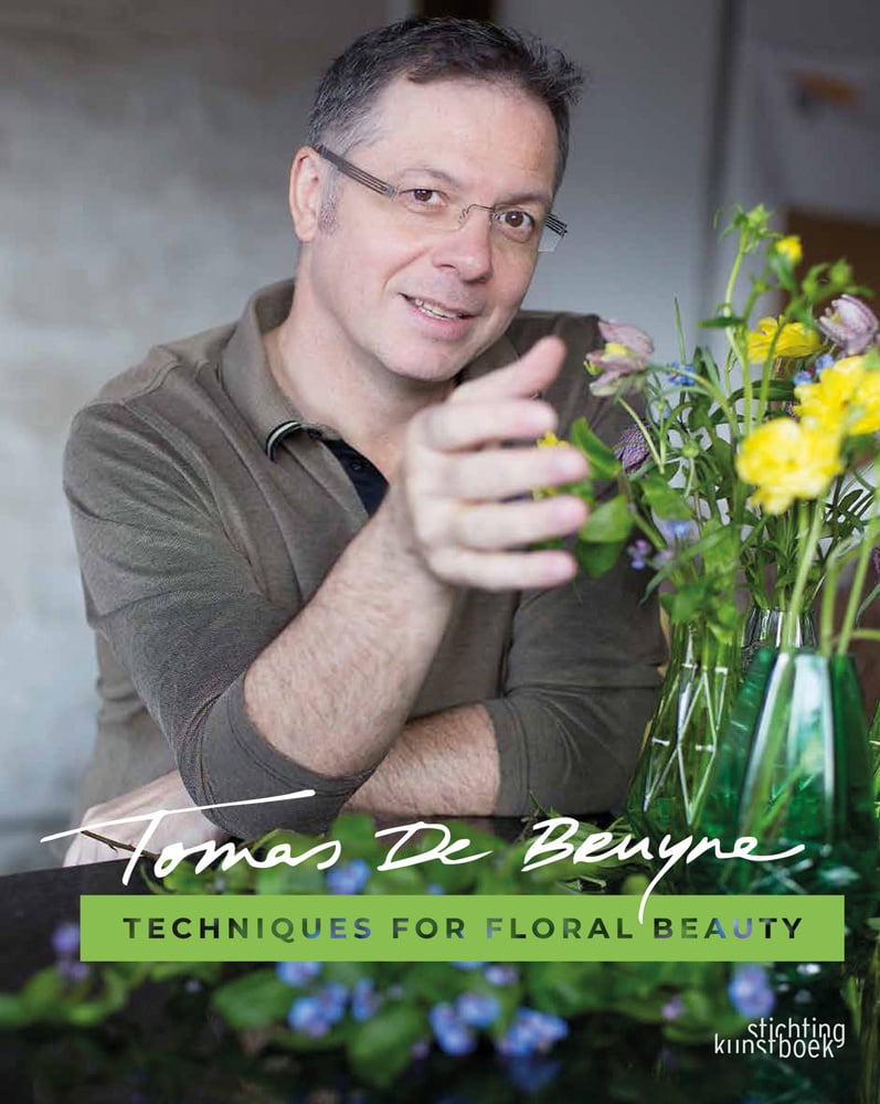 Book cover of Techniques for Floral Beauty, with Tomas De Bruyne sitting at table with vase of yellow and purple flowers. Published by Stichting.