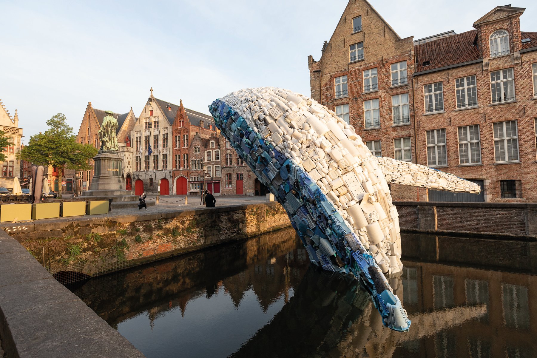 Large red and yellow cocoon installation, floating on water with locks, VLOEIBARE STAD LIQUID CITY, in red font, TRIENNALE BRUGGES 2018 on white border