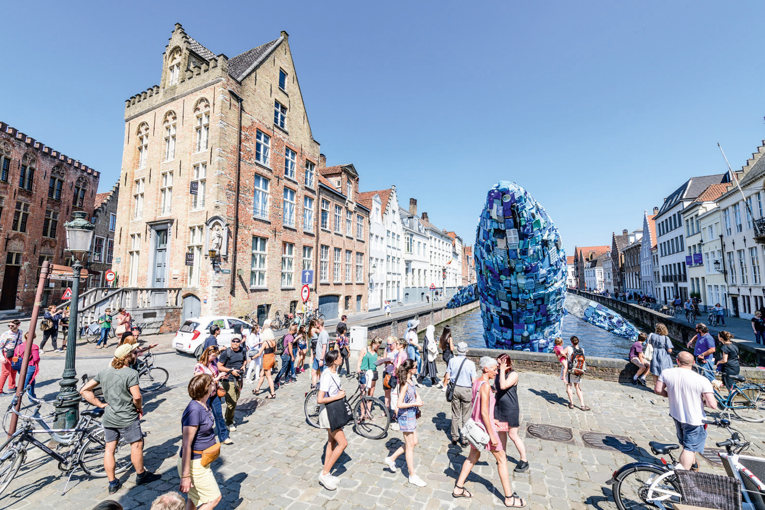 Large red and yellow cocoon installation, floating on water with locks, VLOEIBARE STAD LIQUID CITY, in red font, TRIENNALE BRUGGES 2018 on white border