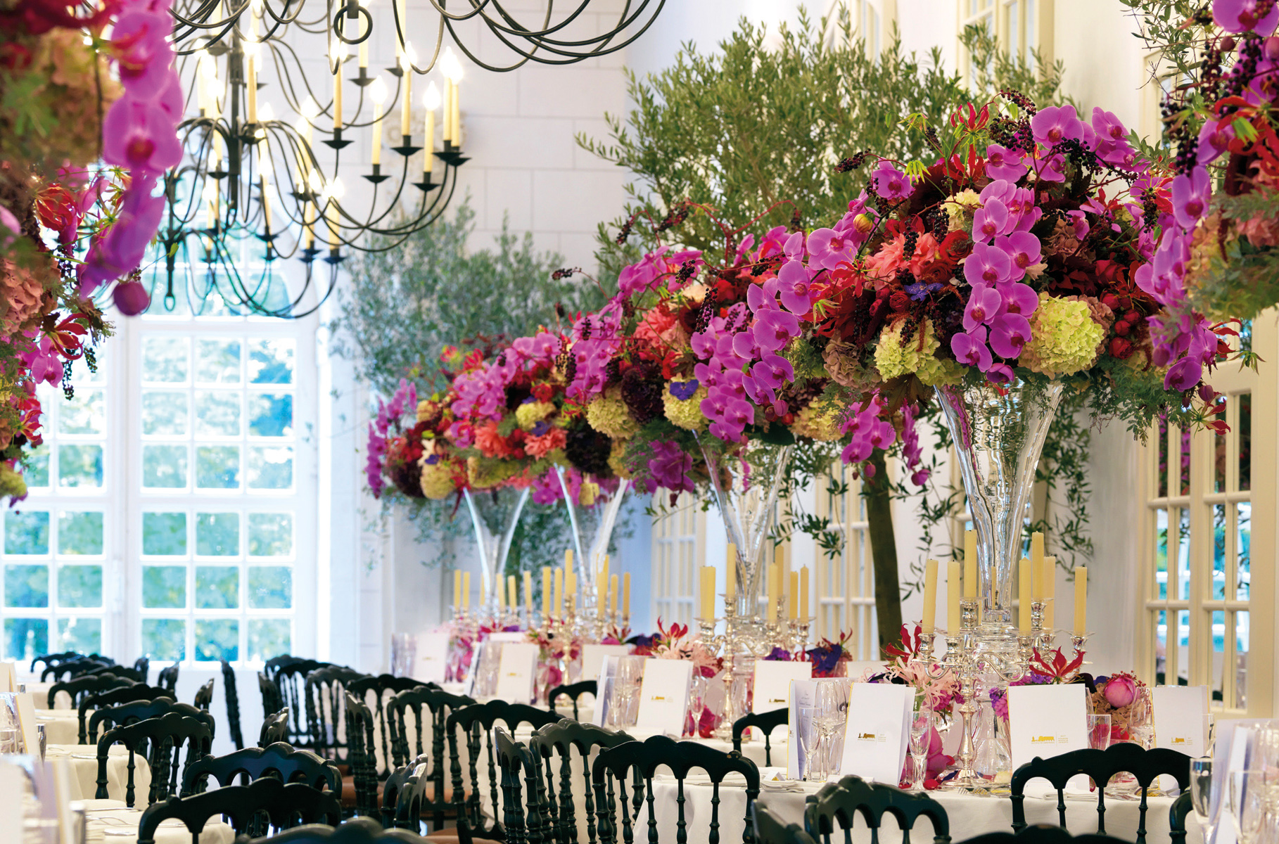 Bouquet of flowers in urn with base, in front of decorative fireplace, THE BOUQUETS OF CHENONCEAU in bright yellow font above.