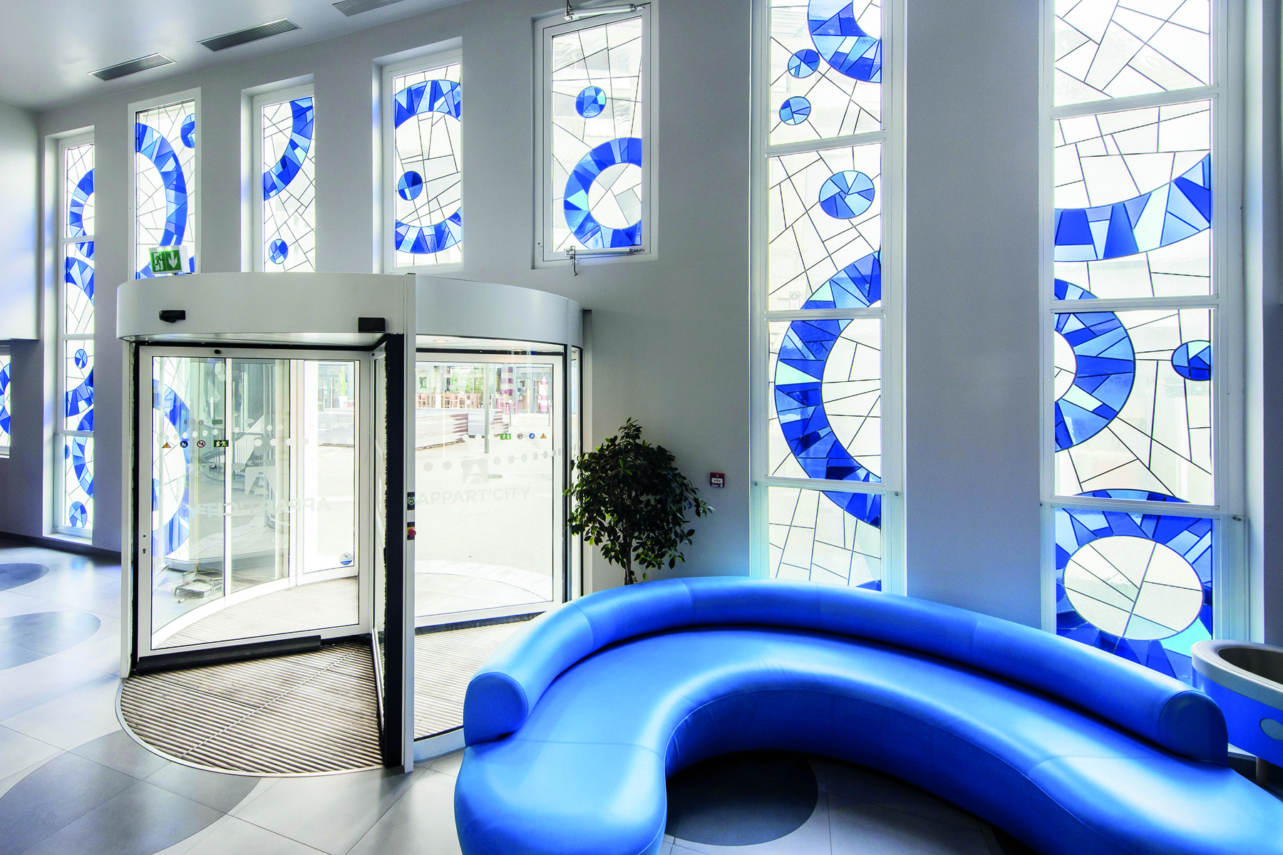 Black outline of art nouveau stained glass design, small blue shape, Artistic Glass Panels in blue and black font near centre
