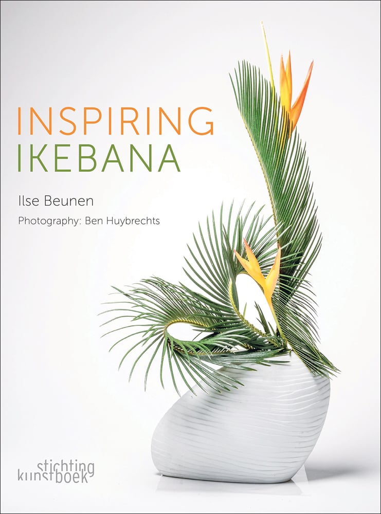 Book cover of Inspiring Ikebana, featuring an ceramic vase with three long green palm leaves and two bird of paradise flowers. Published by Stichting.