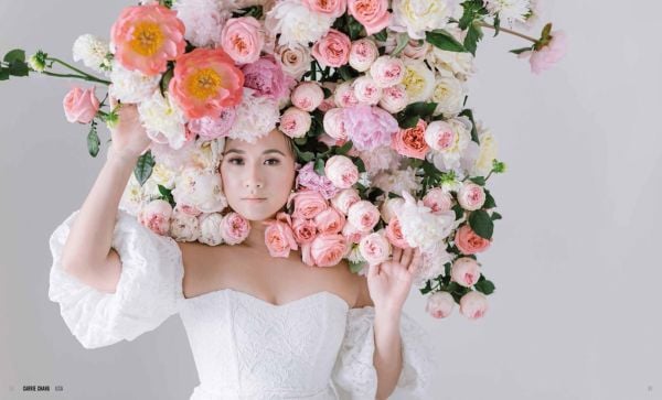 White book cover of International Floral Art 2021/2022, with carnivorous monkey cup plant and foliage made into hummingbird. Published by Stichting.