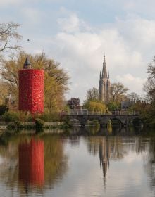 Book cover of Bruges Triennial 2021, TraumA, with a red skeletal platform structure surrounded by green trees. Published by Stichting.