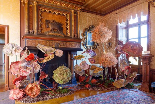 Book cover of The Art of Flower Arranging, Château de Chaumont-sur-Loire featuring a large ornate fireplace with pink, green and white floral arrangement on small dark wood table below. Published by Stichting.