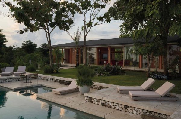 Book cover of Tropical Retreats; featuring an interior living space with wood furniture and bamboo beams. Published by Lannoo Publishers.