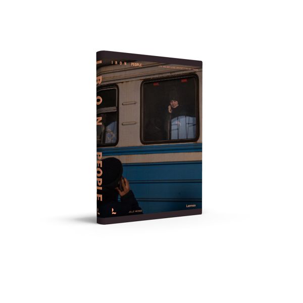 Book cover of Iron People: Life and War Along Ukraine’s Railway Tracks; with person on a mobile phone, looking out of a train window. Published by Lannoo Publishers.