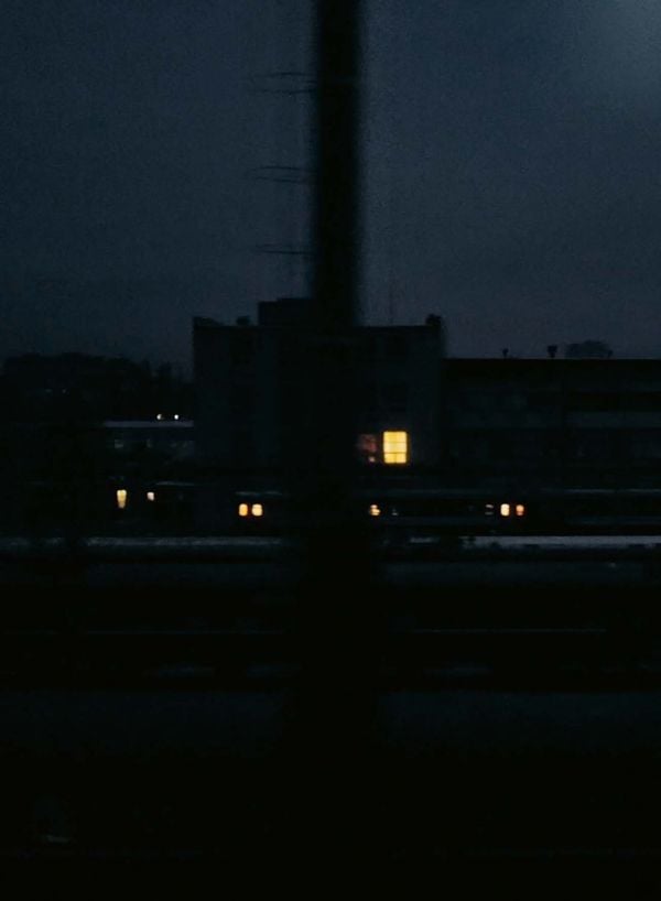 Book cover of Iron People: Life and War Along Ukraine’s Railway Tracks; with person on a mobile phone, looking out of a train window. Published by Lannoo Publishers.