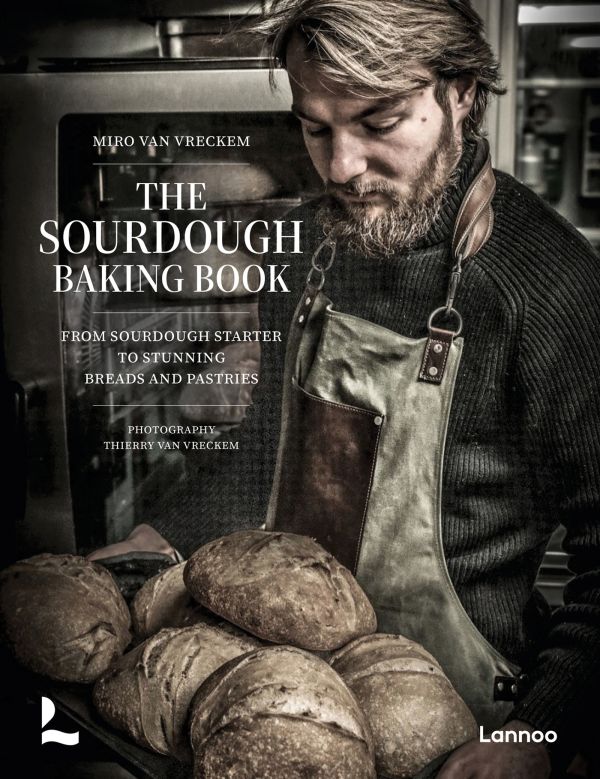 Book cover of The Sourdough Baking Book: From Sourdough Starter to Stunning Breads and Pastries; featuring a baker holding a tray of loaves of bread. Published by Lannoo Publishers.
