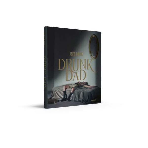 Book cover of Drunk Dad; featuring a photograph of a man sprawled out on a bed in a dimly lit room. Published by Lannoo Publishers.
