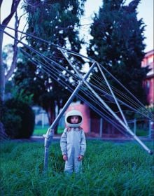 Book cover of The Rocketgirl Chronicles; with a child dress in home made space suit and helmet, sitting on a chair with a radio. Published by Lannoo Publishers.
