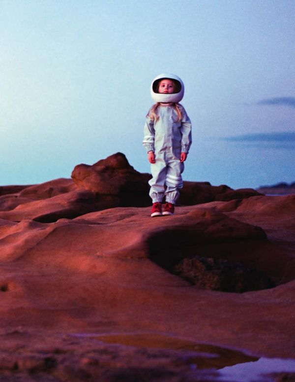 Book cover of The Rocketgirl Chronicles; with a child dress in home made space suit and helmet, sitting on a chair with a radio. Published by Lannoo Publishers.