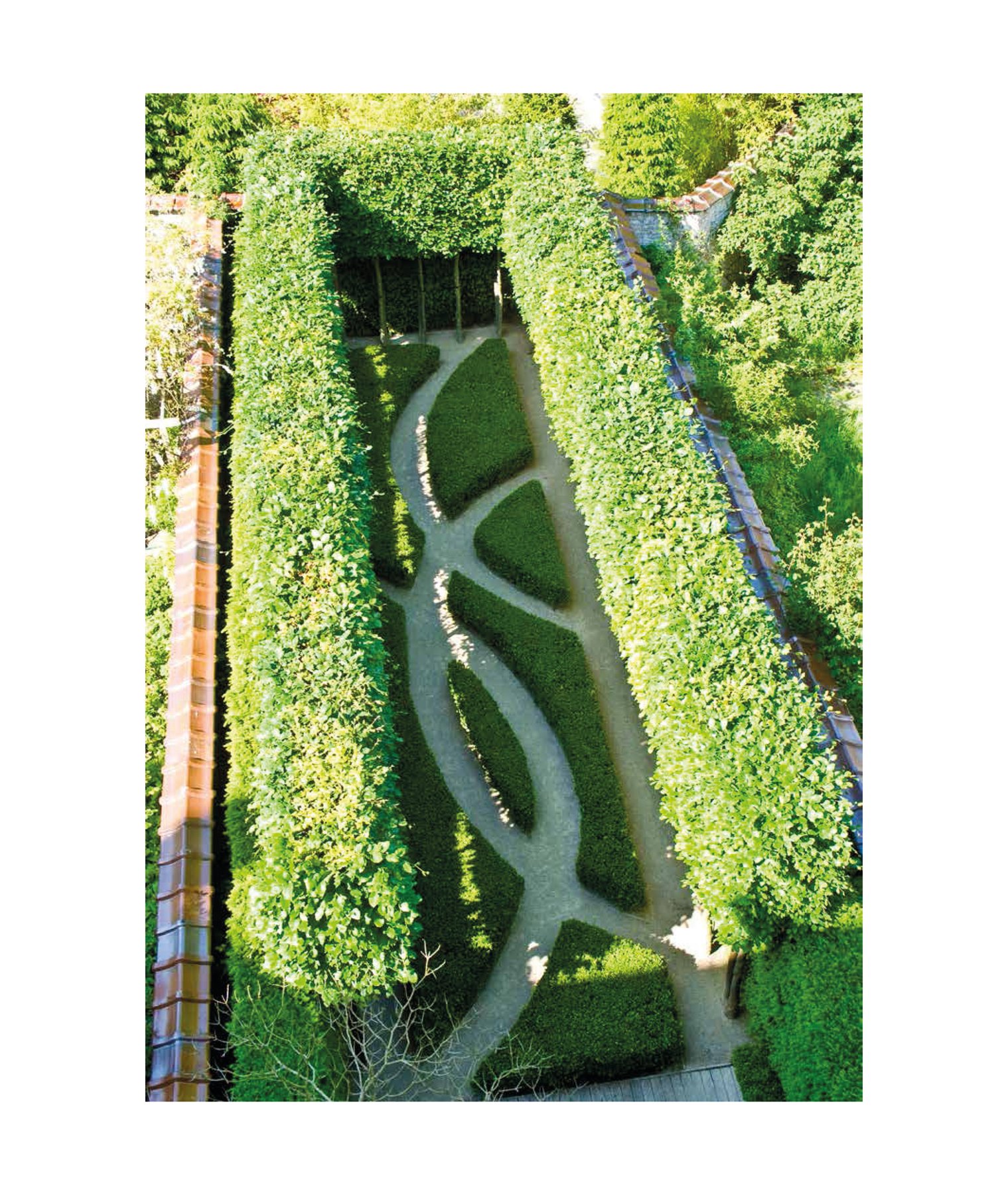 Large green topiary balls edging grass area, with 2 wooden benches, THE WIRTZ GARDENS in white font right of centre