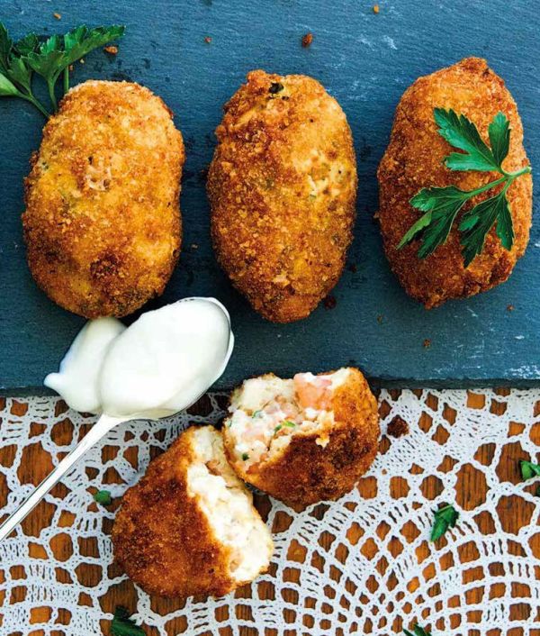 Sandra Alvarez, sea behind, aerial view of octopus with blue foam on slate below, on cover of 'Sandra Alvarez Sensational Spanish Flavors', by Lannoo Publishers..