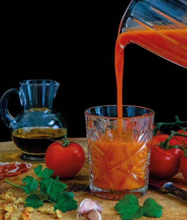 Sandra Alvarez, sea behind, aerial view of octopus with blue foam on slate below, on cover of 'Sandra Alvarez Sensational Spanish Flavors', by Lannoo Publishers..