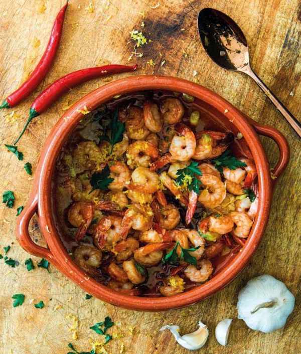 Sandra Alvarez, sea behind, aerial view of octopus with blue foam on slate below, on cover of 'Sandra Alvarez Sensational Spanish Flavors', by Lannoo Publishers..