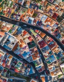 Aerial shot of house surrounded by boats on water, on cover of 'Man Made, Aerial Views of Human Landscapes', by Lannoo Publishers.