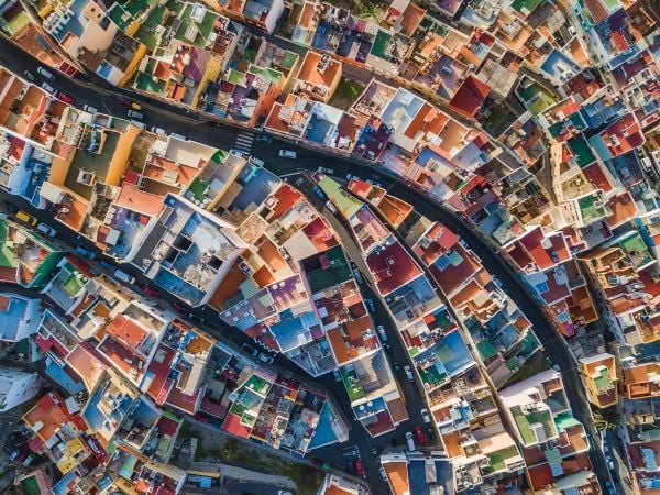 Book cover of Man Made, Aerial Views of Human Landscapes, with an aerial shot of house surrounded by boats on water. Published by Lannoo Publishers.