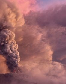 Spectacular shot of volcano spewing bright white and orange lava, on cover of 'Living With Volcanoes', by Lannoo Publishers.