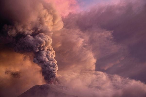 Book cover of Living With Volcanoes, with a spectacular shot of volcano spewing bright orange lava. Published by Lannoo Publishers.