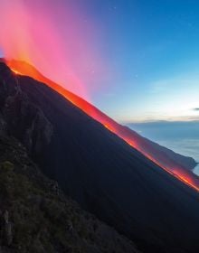 Spectacular shot of volcano spewing bright white and orange lava, on cover of 'Living With Volcanoes', by Lannoo Publishers.