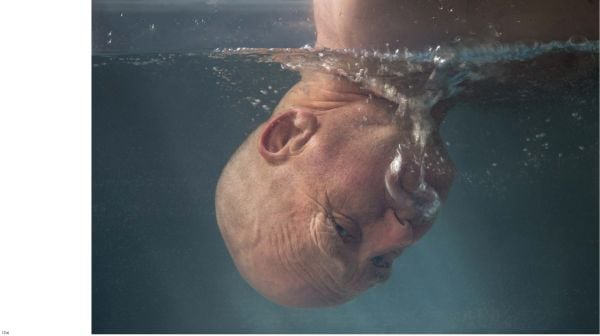 Book cover of Saskia Boelsums. Artist with a Camera, featuring a shiny red pomegranate on white table cloth. Published by Lannoo Publishers.