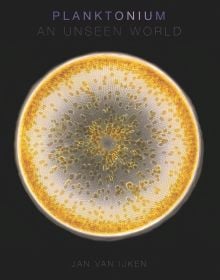 Microscopic photograph of yellow and white circular phytoplankton, on black cover, 'Planktonium', by Lannoo Publishers.