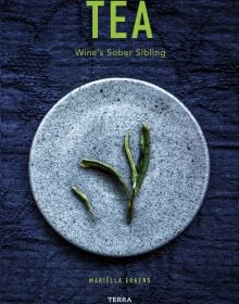 Book cover of Tea', Wine's Sober Sibling, with green tea leaves on blue plate. Published by Lannoo Publishers.