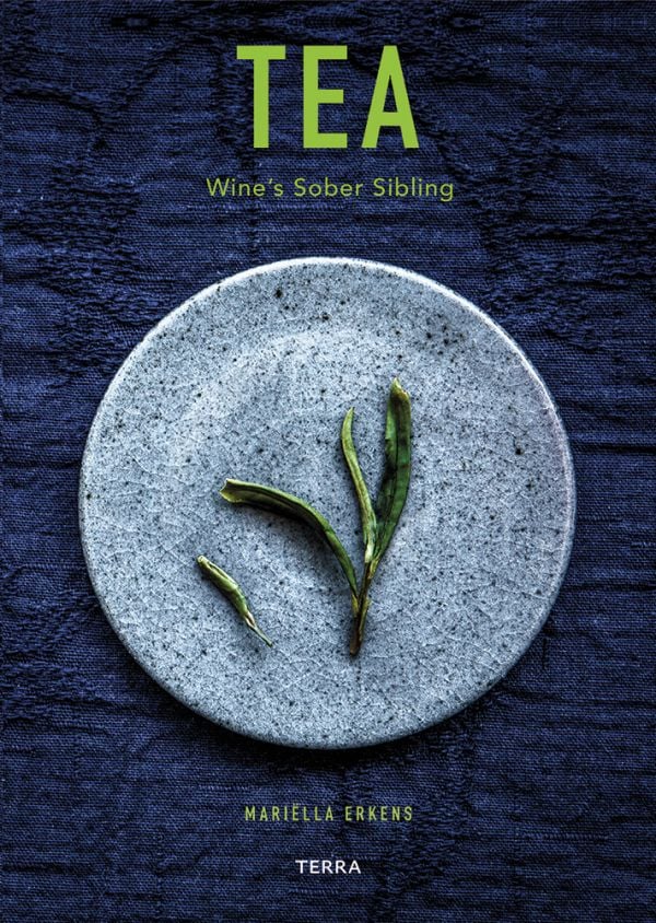 Book cover of Tea', Wine's Sober Sibling, with green tea leaves on blue plate. Published by Lannoo Publishers.