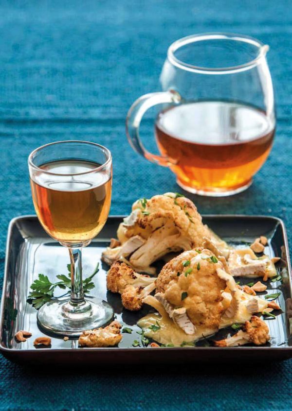 Book cover of Tea', Wine's Sober Sibling, with green tea leaves on blue plate. Published by Lannoo Publishers.