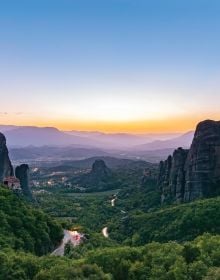 Book cover of Sabine de Milliano's, On the Road in Europe: Unforgettable Scenic Road Trips, featuring a mountainous landscape with waterfall, and winding roads below. Published by Lannoo Publishers.