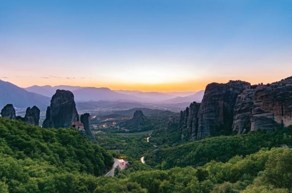 Book cover of Sabine de Milliano's, On the Road in Europe: Unforgettable Scenic Road Trips, featuring a mountainous landscape with waterfall, and winding roads below. Published by Lannoo Publishers.