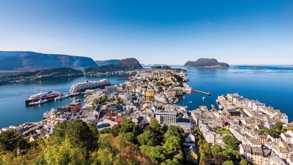 Book cover of Sabine de Milliano's, On the Road in Europe: Unforgettable Scenic Road Trips, featuring a mountainous landscape with waterfall, and winding roads below. Published by Lannoo Publishers.