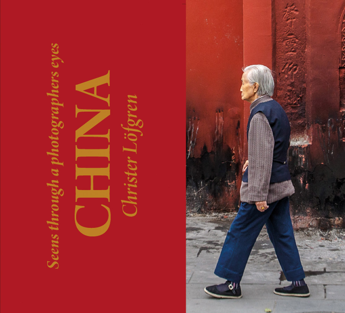 Elderly Chinese man in navy slacks walking through street, Seen Through a Photographers Eyes CHINA in gold font on left red banner.