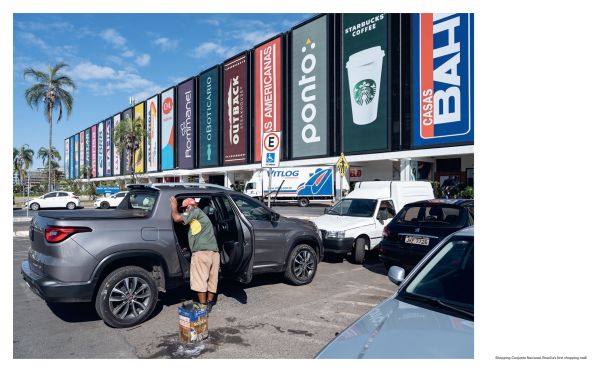 Book cover of New Capital: Building Cities From Scratch, with a construction worker mixing cement, with stone columns behind. Published by Lannoo Publishers.
