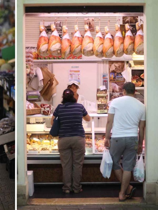 Ham hock with metal hook, tied with string, on charcoal cover of 'Ham, Prime Hams of Europe Stories and Recipes', by Lannoo Publishers.