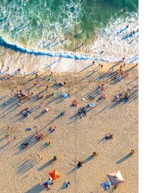Book cover of Wish I Was Here, The World's Most Extraordinary Places on and Beyond the Seashore, with two swimmers in turquoise sea. Published by Lannoo Publishers.