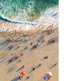 Two swimmers in turquoise sea with rocks, on cover of 'Wish I Was Here, The World's Most Extraordinary Places on and Beyond the Seashore', by Lannoo Publishers.