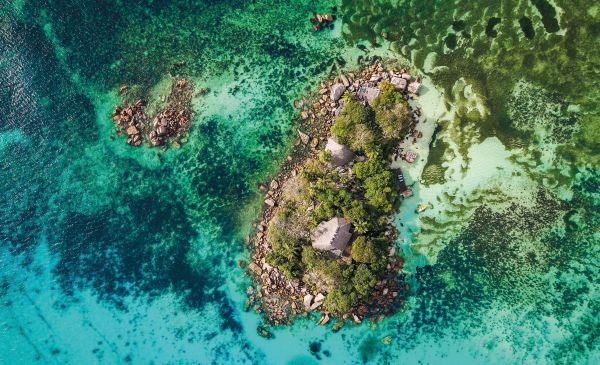 Book cover of Wish I Was Here, The World's Most Extraordinary Places on and Beyond the Seashore, with two swimmers in turquoise sea. Published by Lannoo Publishers.