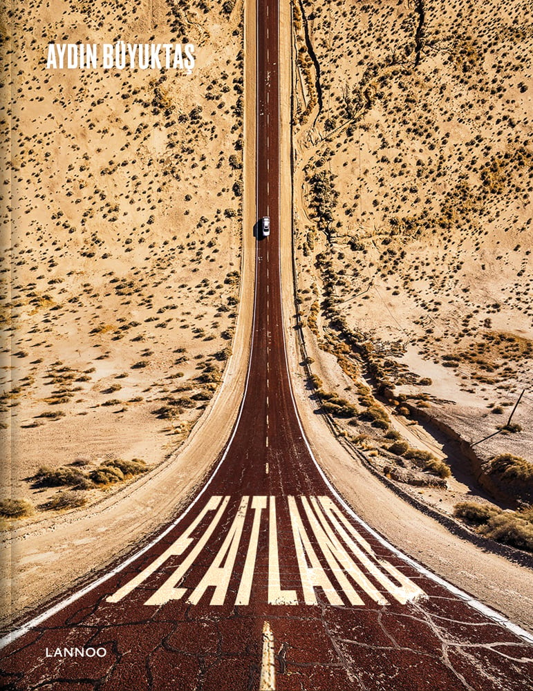 Aerial view of car on road driving through desert, on cover of 'Flatland', by Lannoo Publishers.