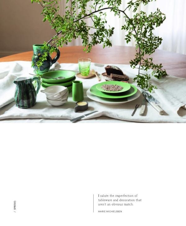 Wood table with vase of flowers, candlesticks, glasses and bowls, on cover of 'Table Stories, Tables for All Occasions', by Lannoo Publishers.