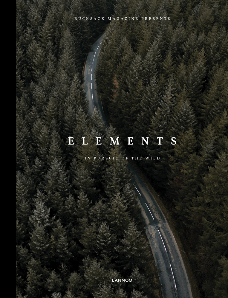 Aerial shot of road winding through green forest trees, on cover of 'Elements, In Pursuit of the Wild', by Lannoo Publishers.